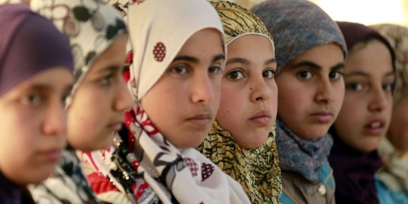 Syrian refugee girls sit at the United Nations Children's Fund (UNICEF) "Child Friendly Spaces" (CFSs) in the Zaatari refugee camp, near the Jordanian border with Syria, on March 8, 2014. The CFSs used as temporary supports that contribute to the care and protection of children in emergencies, responding to childrens rights to protection, psychosocial well-being, and non-formal education. Jordan is home to more than 500,000 Syrian refugees. AFP PHOTO / KHALIL MAZRAAWI        (Photo credit should read KHALIL MAZRAAWI/AFP/Getty Images)